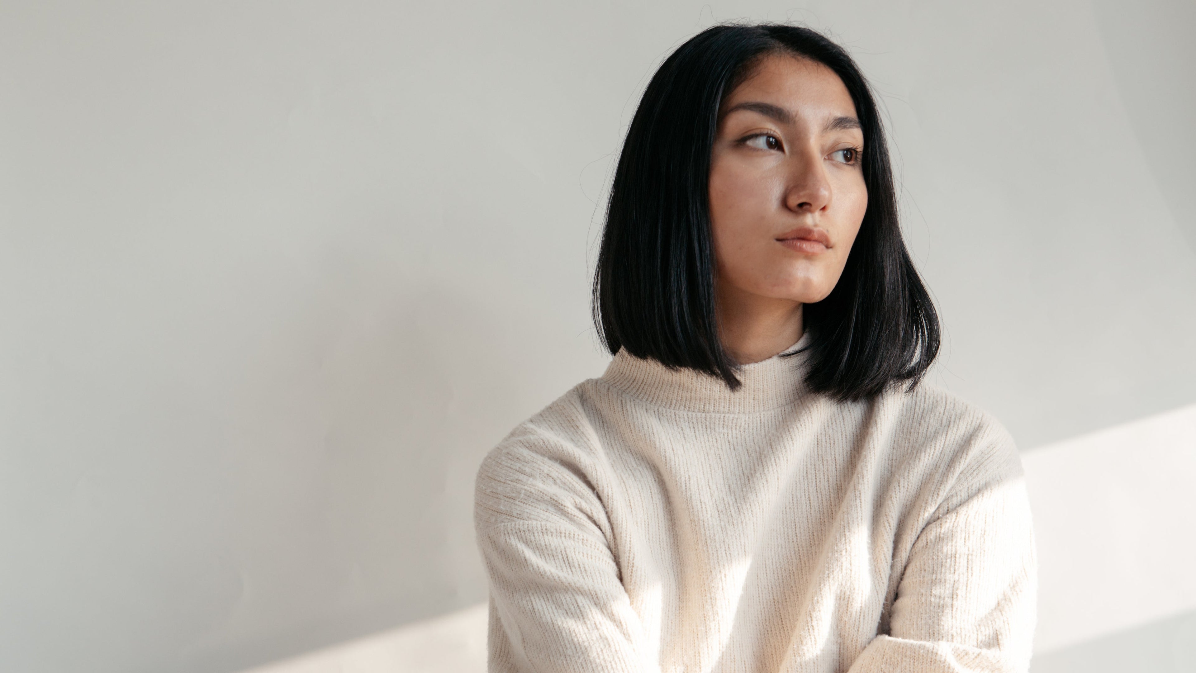 Woman wearing a light-colored sweater against a plain background